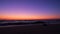 Vivid purple orange gradient sky at dusk on the beach after sunset. Track left.