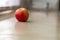 Vivid red apple rests on a kitchen countertop, its glossy skin reflecting the light