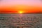 Vivid red glowing sunset over sea with small fishing boat.