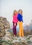 Vivid style concept. Sisters enjoy colorful outfits on gloomy day sky background. Bright mood. Bright sweaters and pants