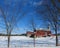 Vivid vintage red barn on hillside in winter snow under deep blue sky above