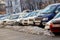 Vladivostok, Russia, 2017 - Cars stand in a dirty roadside. Snowdrift on the background of parked cars