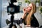 Vlogger female applies lipstick on lips. Beauty blogger woman filming daily make-up routine tutorial at camera on tripod