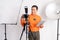 vlogger standing setting camera and holding tablet with lighting equipment