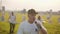 Vocalist with a rock band playing in a large bright field at sunset.