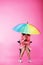 Vogue. Woman in Pink Coat sitting with Colorful Umbrella
