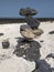 Volcanic black rocks stacked like a pyramid in the sand. Stones of different sizes and shapes stacked and balanced. Apacheta or