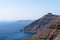 Volcanic high cliffs reaching into the ocean with a blurred view on Oia, Fira, Santorini, Greece