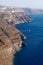 Volcanic high cliffs reaching into the ocean with a sailboat, Fira, Santorini, Greece