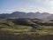 Volcanic landscape with blue river, snow covered mountains, green hills and lava gravel ground covered by lush moss