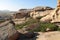 Volcanic layered flat rocks and stones of various shapes with green bushes in the Bektau-Ata tract with a distant view of the