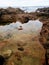 Volcanic peninsula of stones. Large puddles of sea water with reflections