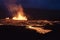 Volcano eruption at Meradalir near Fagradalsfjall, Iceland. Erupting magma and flowing lava at night.