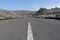 Volcano road in arid island. Straight driveway in rocky landscaped. Asphalt route in black rural field. Canary Island lonely way