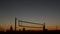 Volleyball net silhouette on beach court at sunset, players on California coast.