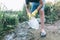 Volunteer boy in blue t shirt picks up dirty plastic bottles in park. Hands in yellow gloves collect garbage