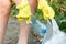 Volunteer boy in blue t shirt picks up dirty plastic bottles in park. Hands in yellow gloves collect garbage