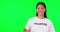 Volunteer, green screen and a woman pointing at space for advertising, charity or information. Face of happy asian