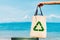 The volunteer holding a plastic bag in to a bin and the sea background .