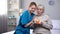 Volunteer hugging elderly lady blowing candle on birthday cake, hospital service