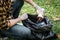 Volunteer man in gloves sitting to picking up coffee cup into plastic black bag for cleaning the park