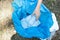 Volunteer tourist hand is clean up garbage and plastic debris on dirty forest by collecting them into big blue bag