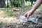 Volunteer tourist hand is clean up garbage and plastic debris on dirty forest by collecting them into big blue bag