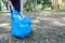 Volunteer tourist hand is clean up garbage and plastic debris on dirty forest by collecting them into big blue bag