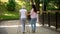 Volunteer walking with elderly woman using walker in hospital park, disability