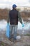 A volunteer wearing a protective mask collects empty bottles. The concept of ecology and environmental protection