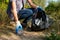 Volunteer woman collecting plastic rubbish in forest. Cleaning environment concept