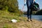 Volunteer woman picking up plastic litter on coast of the river. Cleaning environment concept