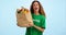 Volunteer woman, vegetables and donation in studio, smile and face with food for charity by blue background. Girl, bag