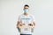 Volunteer work. Young arab man in volunteer t-shirt and medical mask, holding food donations box over light background