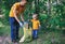 Volunteers activists picking up litter in the park. Father and his toddler son cleaning up forest to save environment from