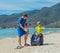 Volunteers blue face mask paradise beach sand lazur sea. Father son pick up garbage into black bag. Problem spilled