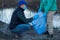 Volunteers collect plastic bottles in bags on the river bank, the concept of ecology and land protection