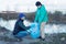 Volunteers collect plastic bottles in bags on the river bank, the concept of ecology and land protection