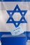 Vote box. Hebrew text Elections 2019 on voting paper over Israel flag background.