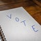 Vote, handwriting  text on paper, political message. Political text on office agenda. Concept of democracy, voting, politics. Copy