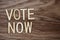 Vote Now Alphabet Letters on wooden background