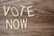 Vote Now Alphabet Letters on wooden background
