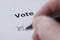 Voting hand of man sets mark in check box with pen - hand and pen blurred