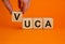 VUCA symbol. Wooden cubes with word `VUCA - volatility, uncertainty, complexity, ambiguity`. Beautiful orange background, copy