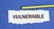 VULNERABLE - word on a torn white paper on a blue background