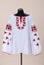 Vyshyvanka Ukrainian national outfit. White textile embroidered shirt on a black manikin. Vyshyvanka with large red