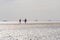 Wadden Sea.People walk along the wattled beach.Silhouettes of people on the horizon of the beach.sandy bottom of the