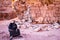 WADI RUM, JORDAN - Nov 2009: A bedouin man in traditional clothing sits next to the ruins of T E Lawrence`s house in Wadi Rum