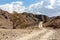 Wadi Shawka hiking trail, winding gravel dirt road through Wadi Shawka riverbed.