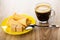 Wafer horns with cream, sugar in saucer, cup with black coffee, spoon on wooden table